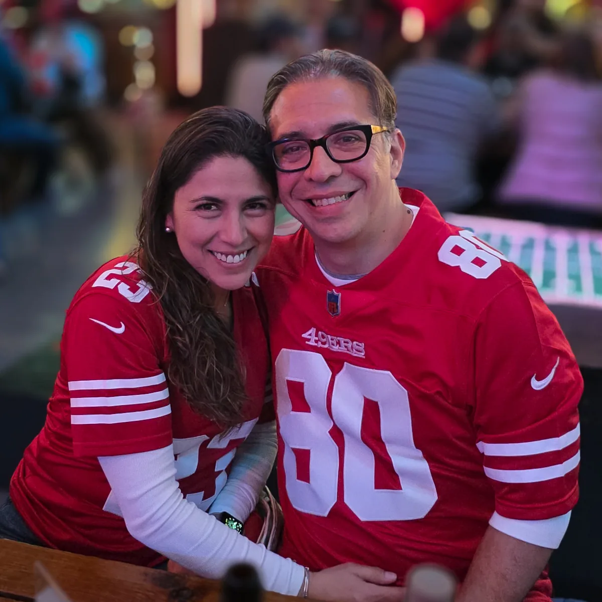 Pareja abrazada con jerseys rojos 23 y 80 de los San Francisco 49ers