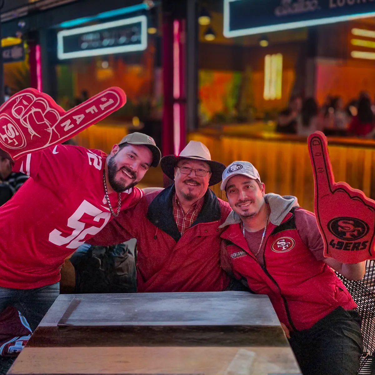 Tres miembros con dedos de hule de los 49ers levantados alrededor de una mesa
