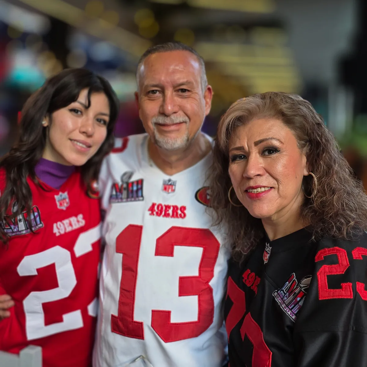 Tres miembros posando con jerseys 13 y 23 de los 49ers en el watch party