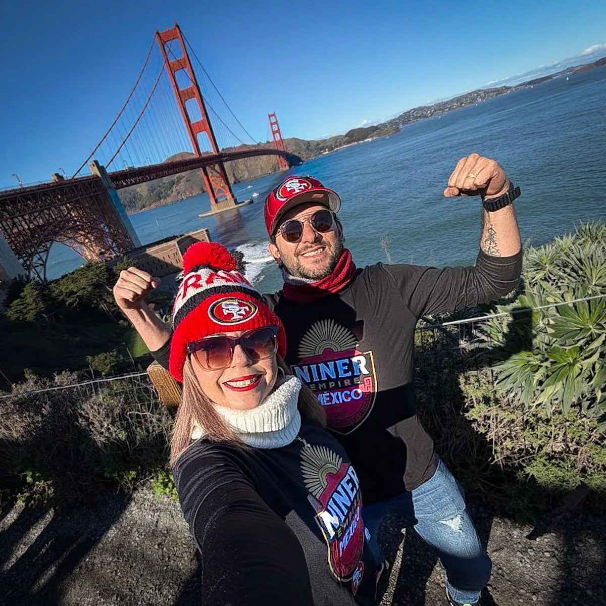 Tres miembros con playeras de Niner Empire México en una selfie frente al puente Golden Gate
