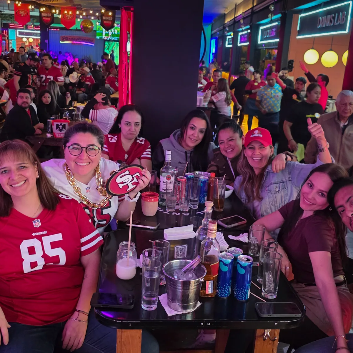 Grupo de miembros en una mesa del watch party con jerseys de los 49ers