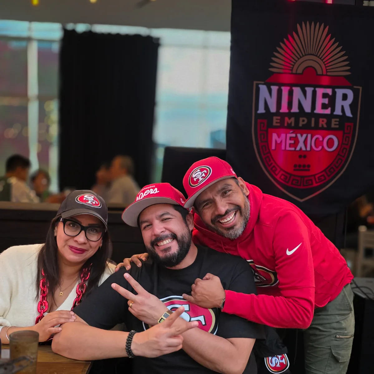 Tres miembros posando frente al estandarte de Niner Empire México